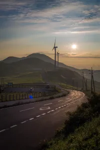 Scenic rural road through Japanese countryside with modern wind turbines on hills